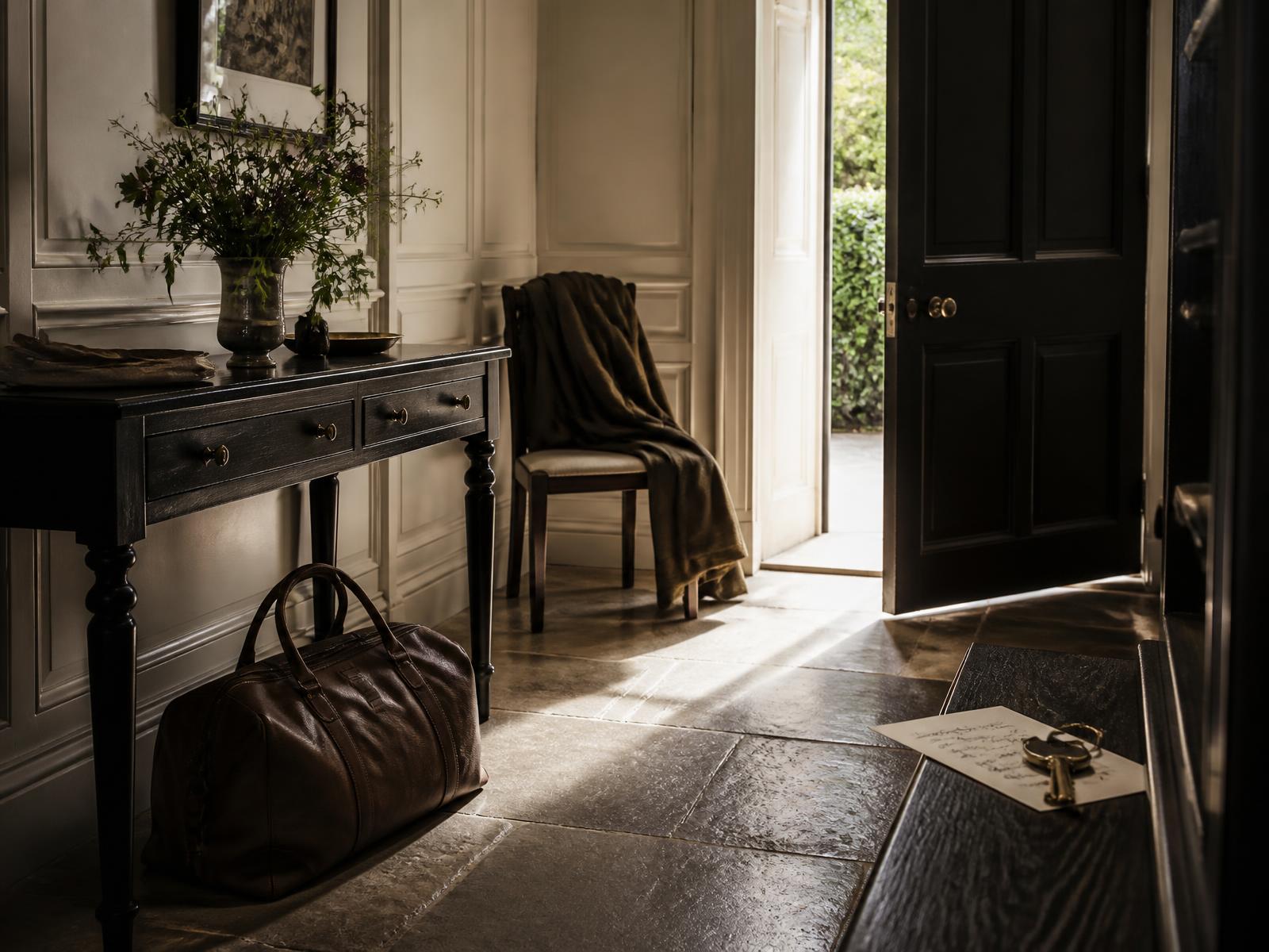 An entrance hall of a private residence prepared for a departure, with a weekend bag, keys and a handwritten note